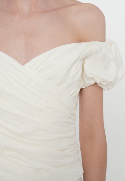 White off-shoulder dress made of textured fabric with gathered puff sleeves and a fitted bodice featuring diagonal ruching.