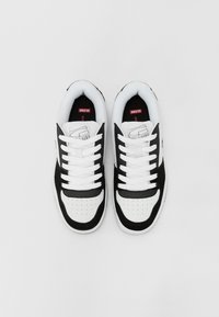 Black and white sneakers with a leather and mesh upper, featuring white laces, perforated toe, and logo on the tongue. Textured sole accents.
