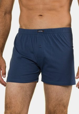 Boxers en coton bleu marine avec taille élastique, dotés d'une fermeture à bouton à l'avant et d'un petit logo en étiquette à la taille. Texture lisse.