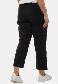 Pantalons noir, cropped, en tissu léger avec une ceinture élastique. Comprend deux poches arrière et des coutures contrastées.