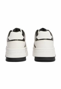 Witte en zwarte sneakers met een gestructureerde bovenzijde, gevoerde kraag en een dikke zool met de tekst "TOMMY JEANS" in reliëf aan de zijkant.
