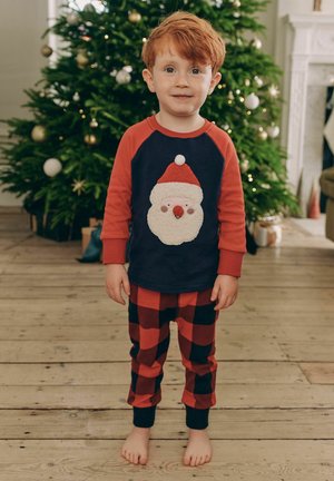 Roter und marineblauer Schlafanzug bestehend aus einem Shirt mit einem Santa-Gesicht und schwarz-rot karierter Hose. Weicher Stoff und lockere Passform.