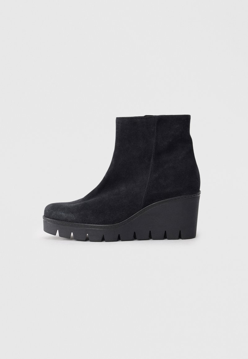 Bottines en suède noir avec un talon compensé haut, un bout arrondi et une semelle en caoutchouc texturé avec des bords crantés.