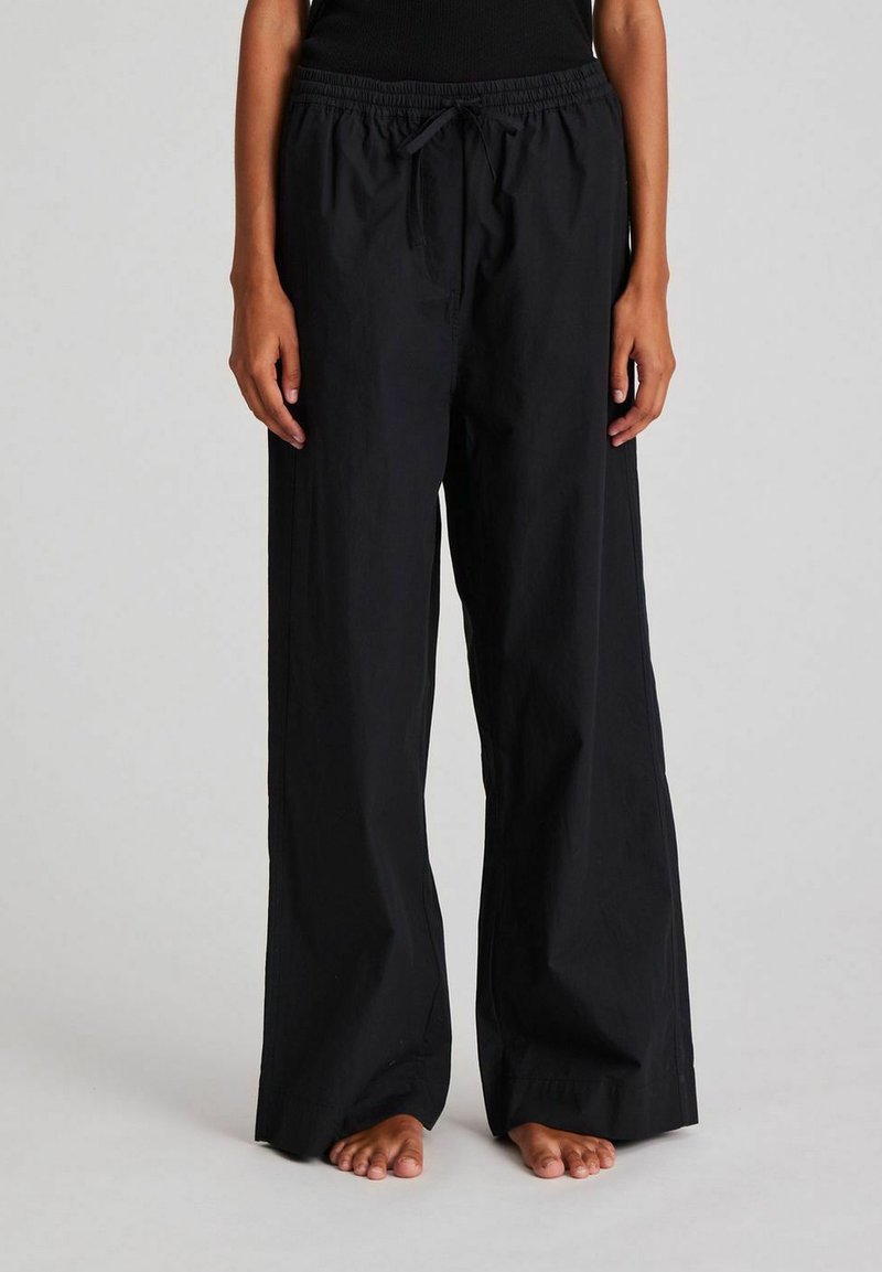 Loose-fitting black pants made of lightweight fabric. Features an elastic waistband with drawstring and a straight, wide leg design.