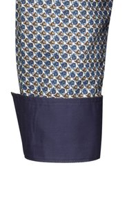 Camicia a maniche lunghe con un motivo geometrico multicolore, dotata di polsini blu navy e un tessuto chiaro a contrasto con texture.