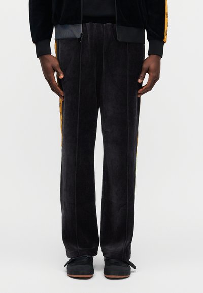 Μαύρο βελούδινο παντελόνι φόρμας με κίτρινες ρίγες στο πλάι. Διαθέτει ίσια γραμμή, απαλό ύφασμα και άνετη εφαρμογή. Διακοσμημένο με φερμουάρ στη μέση.