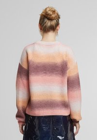 Gebreide trui met een gradiëntpatroon in tinten roze, oranje en paars. Losse pasvorm, geribde textuur en ronde hals.