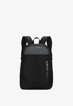 Zaino nero realizzato in tessuto resistente, con un pannello superiore grigio, due spallacci e una tasca laterale in rete. Include un accento con il logo.
