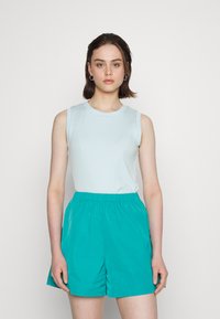 Top sem mangas azul claro combinado com calções de cintura elástica turquesa. O tecido parece suave e leve, com um ajuste descontraído.
