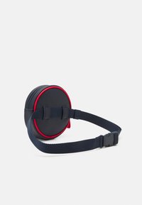 Pochette rotonda in pelle blu navy con accenti rossi, chiusura con zip e tracolla regolabile blu navy. Presenta un retro piatto per un attacco sicuro.