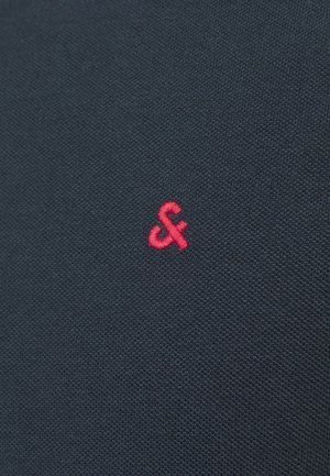 Tissu texturé bleu marine avec un petit logo rouge brodé en forme d'esperluette, situé près du coin inférieur droit.