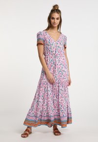 Rochie maxi roz cu flori, cu mâneci scurte, decolteu în V și tiv cu volane în straturi. Prezintă accente colorate multicolore la mâneci și tiv.