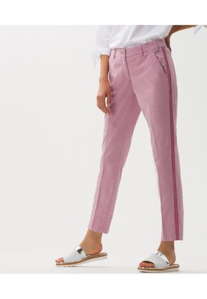 Person wearing light pink pants with a dark pink side stripe and white slide sandals, standing against a plain white background.