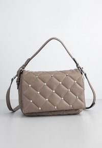 Quiltet beige skuldertaske med sølvnitter, der har et top håndtag og en justerbar skulderrem. Blødt materiale med en tekstureret overflade.