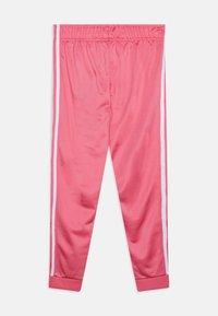 Różowe legginsy sportowe wykonane z gładkiej tkaniny, z białymi paskami po bokach i mankietami przy kostkach, z elastycznym paskiem w talii dla wygody.