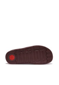 Bruine rubberen buitenzool met een getextureerde grip, voorzien van het "fitflop" logo, een ronde rode accent en een zigzag loopvlakpatroon voor tractie.