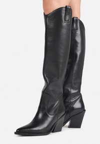 Black leather knee-high boots with a pointed toe, stacked heel, and vertical seams. Features a pull tab at the top for ease of wear.