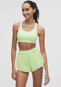 Világoszöld sportmelltartó és azonos színű sort, sima anyagból készült. A sort elasztikus derékkal rendelkezik, és laza, kényelmes fazonú.
