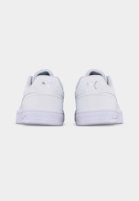 Ζευγάρι λευκών παπουτσιών Puma, εμφανιζόμενα από πίσω, με το λογότυπο Puma στις φτέρνες και λευκές λαστιχένιες σόλες.