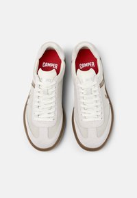 Weiße Sneaker mit Obermaterial aus Textil und Rauleder, brauner Gummisohle, Mesh-Akzenten und rotem Innenfutter mit "CAMPER"-Logo. Die Schnürsenkel sind weiß.