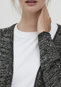 Gray and black textured cardigan overlaps a white T-shirt. The cardigan features an open front and long sleeves with a slightly ribbed cuff.