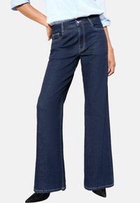 Jeans de pierna ancha de color azul oscuro, confeccionados en denim, con bolsillos delanteros, cintura alta, costuras blancas en contraste y un diseño limpio y sencillo.