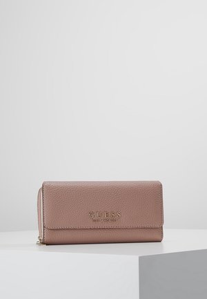 Blushroze gestructureerde leren portemonnee van GUESS met goudkleurig logo, klepsluiting en rits, op een witte displayoppervlakte met grijze achtergrond.