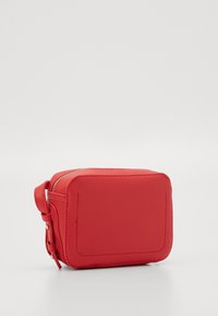 Röd läderväska med dragkedja, i rektangulär form, med slät yta och en sidrem. Har accentuerad sömnad och rundade hörn.