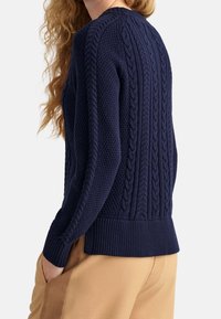 Granatowy sweter z dzianiny z teksturowanym wzorem warkocza, ściągaczami na mankietach i u dołu. Wykonany z średniej grubości materiału dla komfortu.