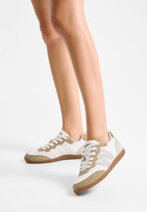 Weiße und beige Sportschuhe mit strukturiertem Obermaterial, Wildlederelementen, Schnürverschluss und Gummisohle; seitliche Perforationen für Atmungsaktivität.