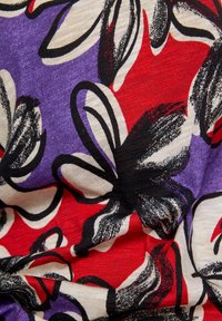 Blumenstoff mit einer Mischung aus roten, lila und beigen Farbtönen. Merkmale kräftige, skizzierte schwarze Umrisse. Glatte Textur mit einem leicht zerknitterten Aussehen.