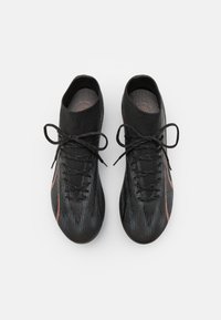 Scarpe da ginnastica nere con una tomaia testurizzata, caratterizzate da un vivace accento arancione, lacci e una vestibilità aderente simile a quella di un calzino.