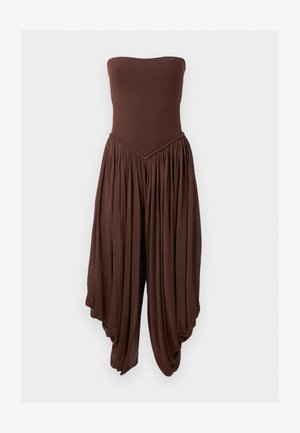 Barna, pánt nélküli overall, testhez simuló felsőrésszel és széles, redőzött, redőzött nadrággal, amely légies sziluettet alkot.