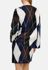 Sweter dzianinowy w wzór diamentu w kolorze granatowym, czarnym, brązowym i kremowym. Posiada luźny krój i dekoracyjne białe akcenty w stylu haftu.