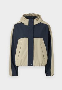 Färgblockerad jacka med en beige och marinblå design, utrustad med huva, dragkedja fram, elastisk nederkant och framfickor. Lättviktig tygtextur.