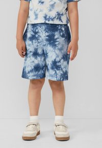 Pantaloni corti blu tie-dye realizzati in tessuto morbido, con vita regolabile e un fit rilassato. Abbinati a scarpe bianche e calzini alla caviglia.