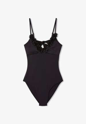 Costume da bagno intero nero con spalline sottili, decorazioni floreali attorno al collo e una texture liscia e opaca. Cintura regolabile sul davanti.