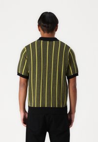 Short-sleeve knitted sweater featuring vertical black and neon yellow stripes, ribbed collar and cuffs, and a fitted silhouette.