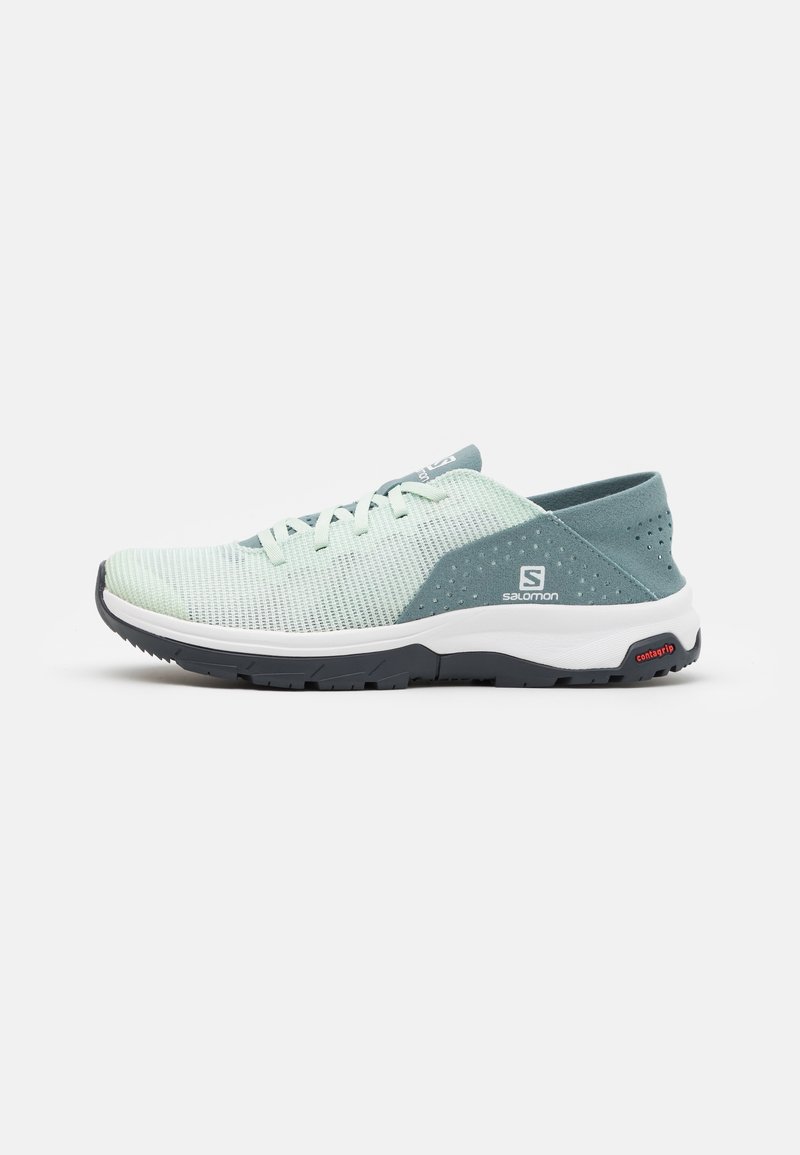 Light green mesh athletic shoe with a padded collar, grey accents, white midsole, and black outsole featuring a textured pattern.