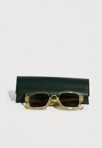 Läpinäkyvät keltaiset suorakaiteen muotoiset aurinkolasit tummilla linsseillä, mukana tummanvihreä nahkainen kotelo, jossa on kohokuviollinen logo.