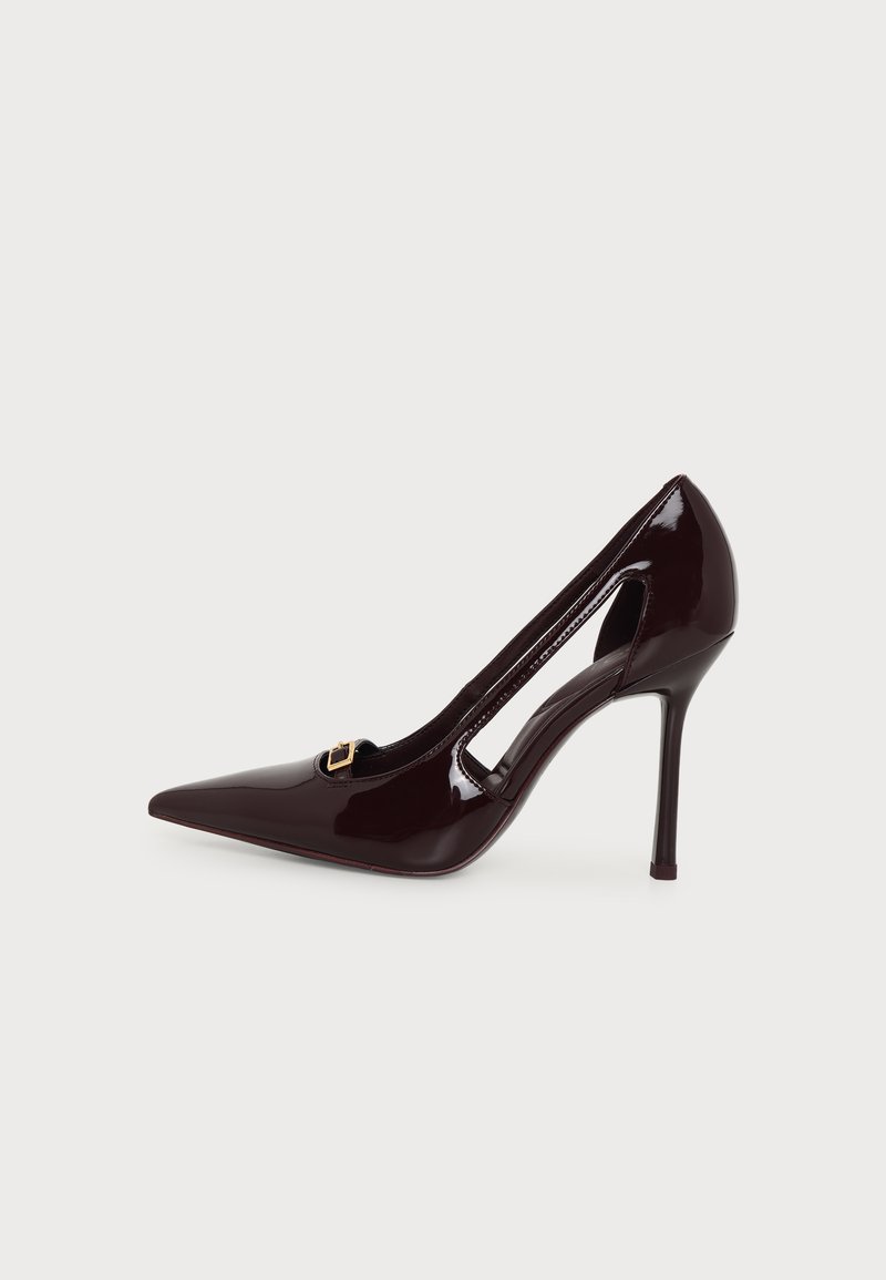 Escarpin en cuir verni bordeaux foncé à talon haut avec bout pointu, découpe latérale et petit détail boucle dorée sur fond uni.