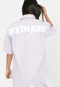 Överdimensionerad lila skjorta med korta ärmar, med en stor vit "SIXTH JUNE" logotyp på baksidan. Slät tyg och avslappnad passform.