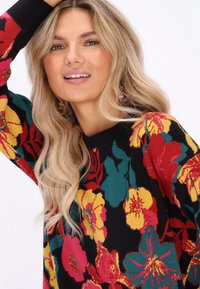 Maglione nero con un vivace motivo floreale in rosso, giallo e teal. Collo a coste e vestibilità comoda. Maniche lunghe con dettagli stampati colorati.