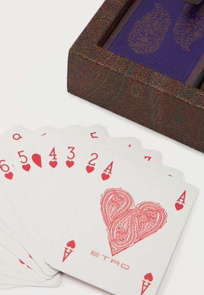 Playing cards fanned out showing hearts from 2 to Ace with a decorative heart design and a brown textured card box partially visible.