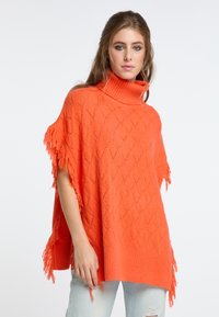 Poncho de punto naranja con patrón de diamante, cuello alto y detalles de flecos en las mangas. Textura suave y corte holgado.