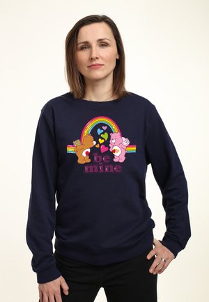 Mørkeblå sweatshirt med grafik af to farverige bjørne og en regnbue, med teksten "be mine" i fed skrift. Blødt materiale, løs pasform.
