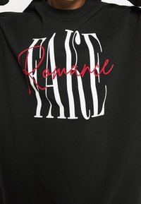 Sudadera negra con letras en bloque blancas que dicen "RACE" y texto en cursiva roja "Romance" que se superponen en el pecho.