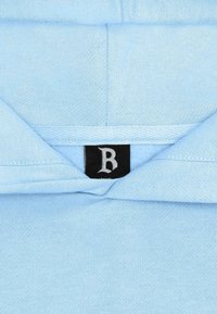 Light blue pullover with a soft texture, featuring a black tag with a white "B." The collar lays flat with a clean design.