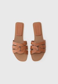 Sandalias deslizantes de cuero marrón con un diseño de tiras entrelazadas y un detalle decorativo de nudo, y suela plana.