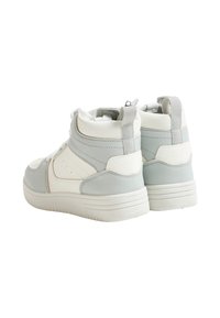 Wysokie trampki wykonane z miękkiej szarej i białej skóry, z teksturowanymi panelami, sznurowadłami i małą pętlą z tyłu.